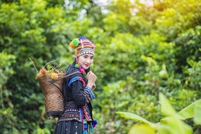 Beautiful woman looking away while standing against trees