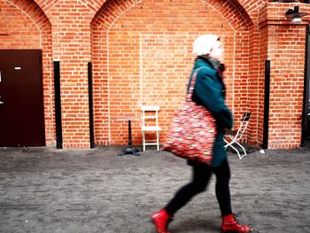 Full length of woman sitting on brick wall