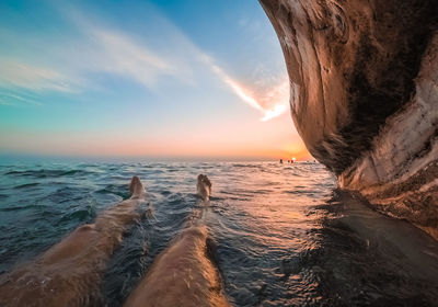 A man lies in the water under white rocks in abkhazia at sunset