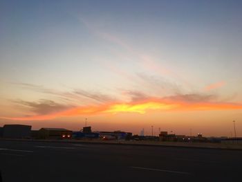 Silhouette of city against cloudy sky during sunset