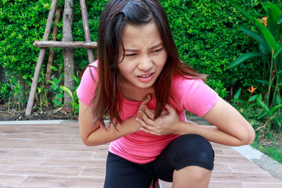 Woman suffering from chest pain kneeling on footpath