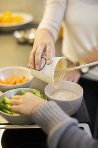 Cropped image of mother and daughter preparing salad