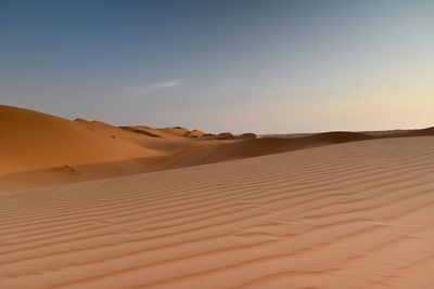 Sand dunes in desert against sky