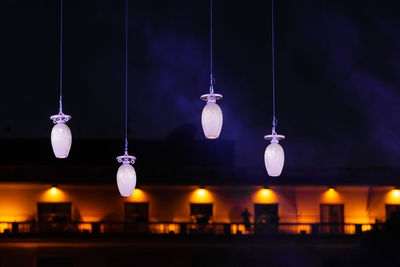 Illuminated light bulbs hanging from ceiling at night