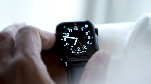 Close-up of person hand holding clock on table