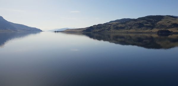 Scenic view of lake by mountains against sky