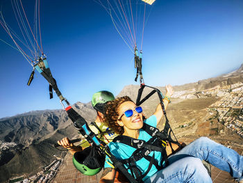 Low angle view of woman swinging against mountain