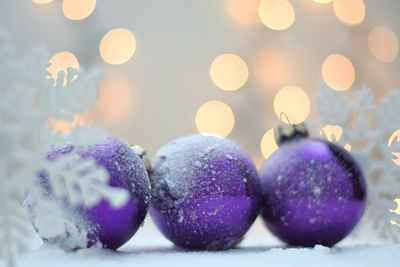 Close-up of purple baubles on snow during christmas