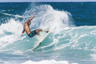 Shirtless man surfing in sea