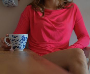 Midsection of woman having coffee at home