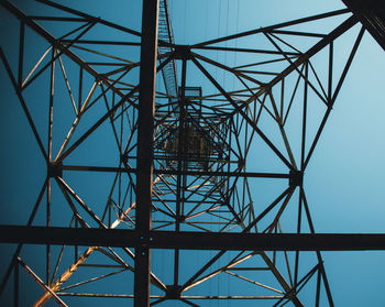 Low angle view of electricity pylon against blue sky