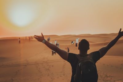 Rear view of person standing on beach against sky during sunset