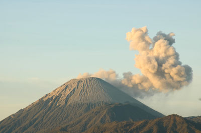 Smoke emitting from volcanic mountain against sky