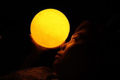Close-up of woman holding illuminated lighting equipment at night