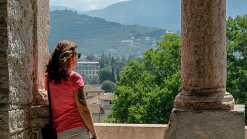 Side view of woman standing by tree against mountain