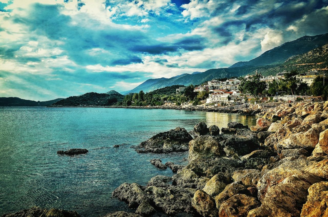 mountain, water, sky, cloud - sky, mountain range, scenics, building exterior, tranquil scene, sea, built structure, beauty in nature, architecture, tranquility, cloud, nature, lake, cloudy, rock - object, idyllic, river