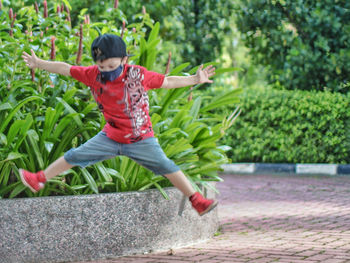 Full length of girl jumping on plant