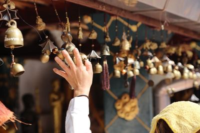 Cropped image of person touching bells hanging at temple