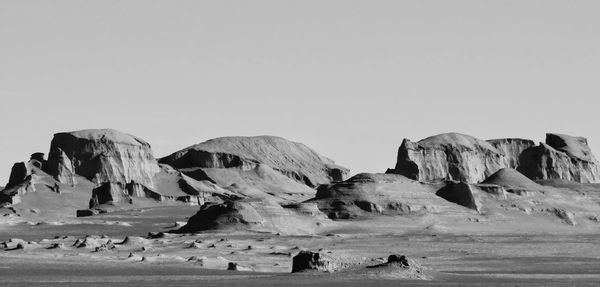 Group of people on rocks against clear sky