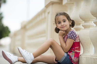 Portrait of smiling cute girl sitting outdoors