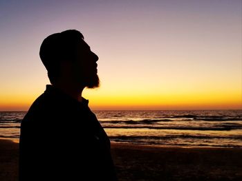 Silhouette man looking at sea against sky during sunset