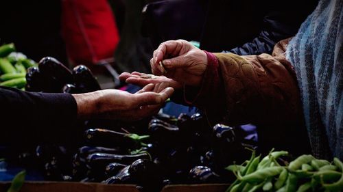 Man giving coin to customer at vegetable stall