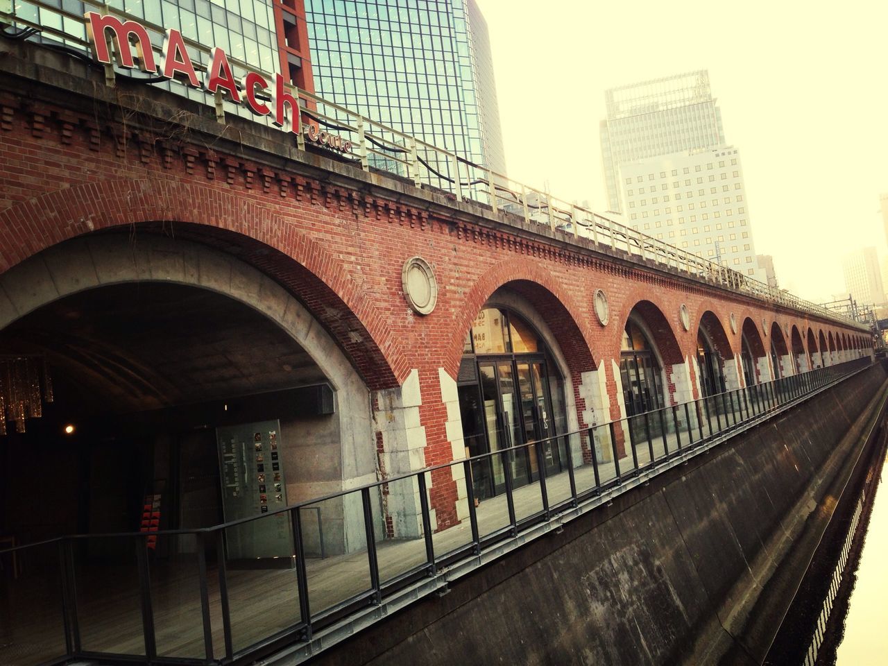 architecture, built structure, building exterior, city, transportation, building, red, day, low angle view, sky, outdoors, modern, city life, no people, public transportation, rail transportation, railroad track, clear sky, window, arch