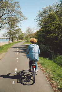 Rear view of woman riding bicycle on road