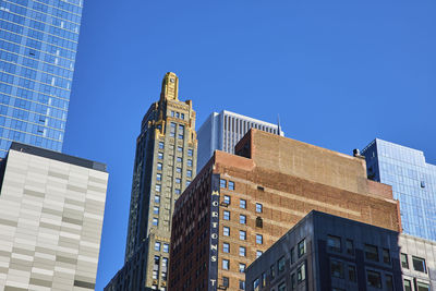 Low angle view of skyscrapers against clear blue sky