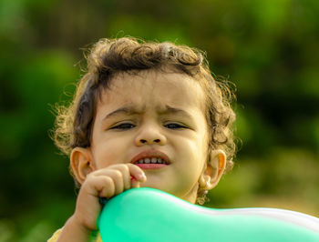 Close view of a small child's face and holding a blue balloon