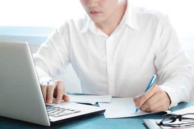 Midsection of man using laptop on table