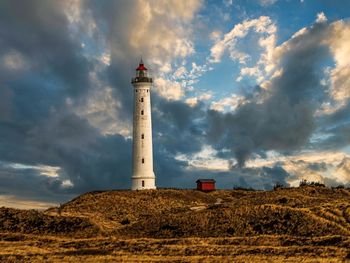 Lighthouse by sea against sky