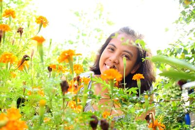 Portrait of smiling young woman against yellow flowering plants
