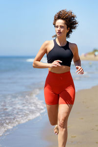 Young woman with arms outstretched standing at beach