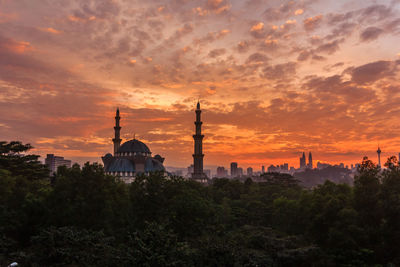 Panoramic view of buildings and trees against sky during sunset