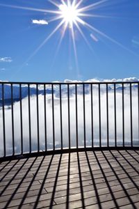 Railing on bridge against bright sky during foggy weather