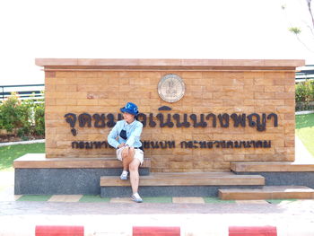 Full length of woman sitting against built structure