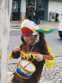 Woman holding umbrella by street in city