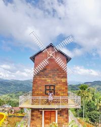 Traditional windmill on mountain against sky