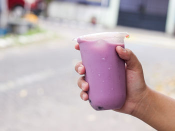 Close up hand holding ice milk taro flavour with bobba inside