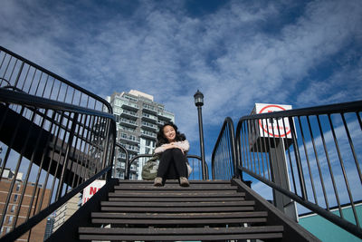 Low angle view of woman standing on footbridge