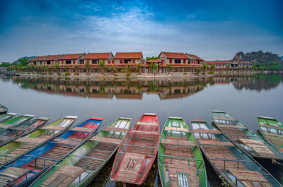 Buildings by lake and boats against sky in city