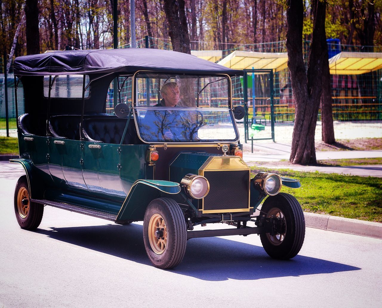 transportation, mode of transportation, land vehicle, real people, street, tree, road, day, city, car, sitting, motor vehicle, men, plant, nature, travel, one person, sunlight, outdoors