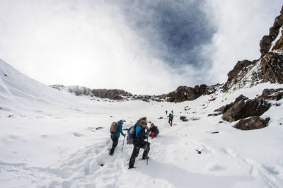 People skiing on snowcapped mountains against sky