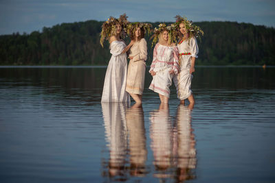 Rear view of women standing by lake
