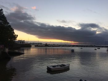 Boat moored on river against sky during sunset