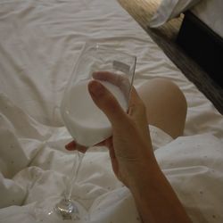 High angle view of woman hand holding coffee cup on bed