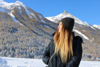Beautiful woman wearing knit hat standing against snowcapped mountain