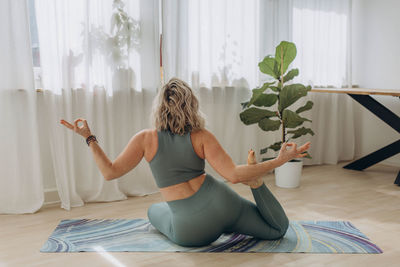Rear view of woman sitting on bed at home
