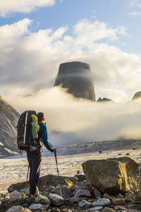 Backpacker looking up at the summit of mount asgard, baffin island.